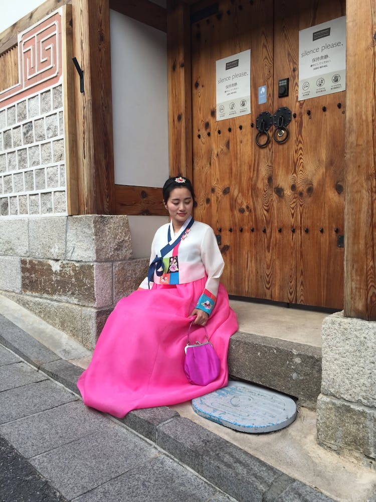 Photo Of A Young Woman In A Skirt Sitting In Front Of A Door