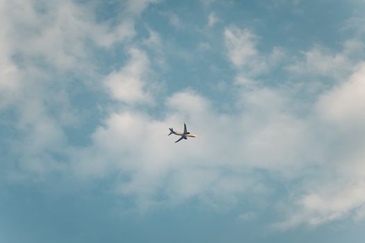 An airplane soars amidst fluffy clouds, captured in a clear blue sky over Mexico City.