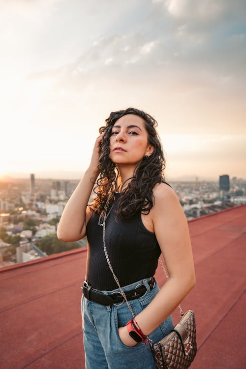 Woman Posing on a Red Roof, and Cityscape in Background