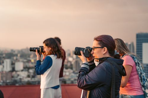 Free Group of photographers capturing the Mexico City skyline during sunset from a rooftop vantage point. Stock Photo
