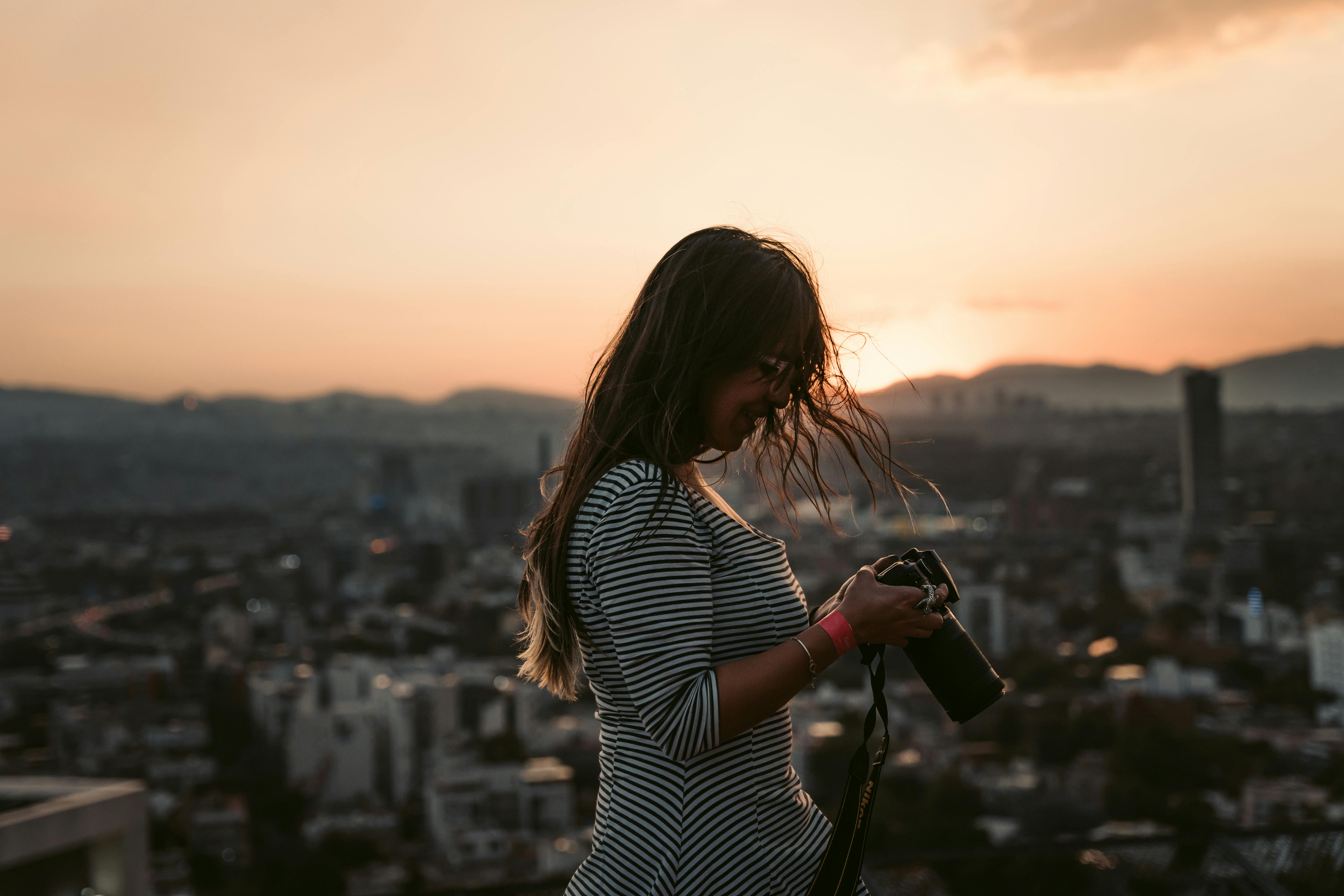 A woman photographs a stunning Mexico City skyline at sunset, creating a perfect urban panorama.