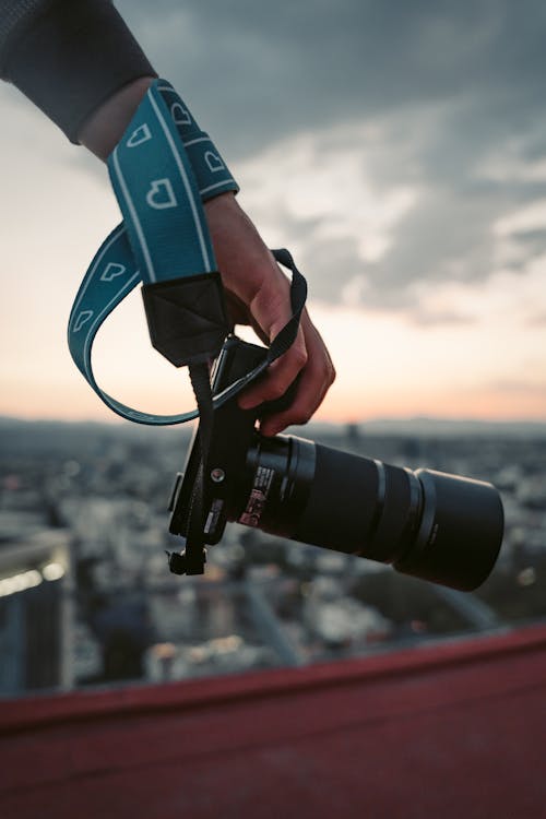 Hand Holding Camera with City behind at Sunset
