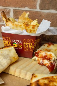 Close-up of Pizza Crek wraps in takeout packaging, showcasing crispy flatbread and rich tomato filling.