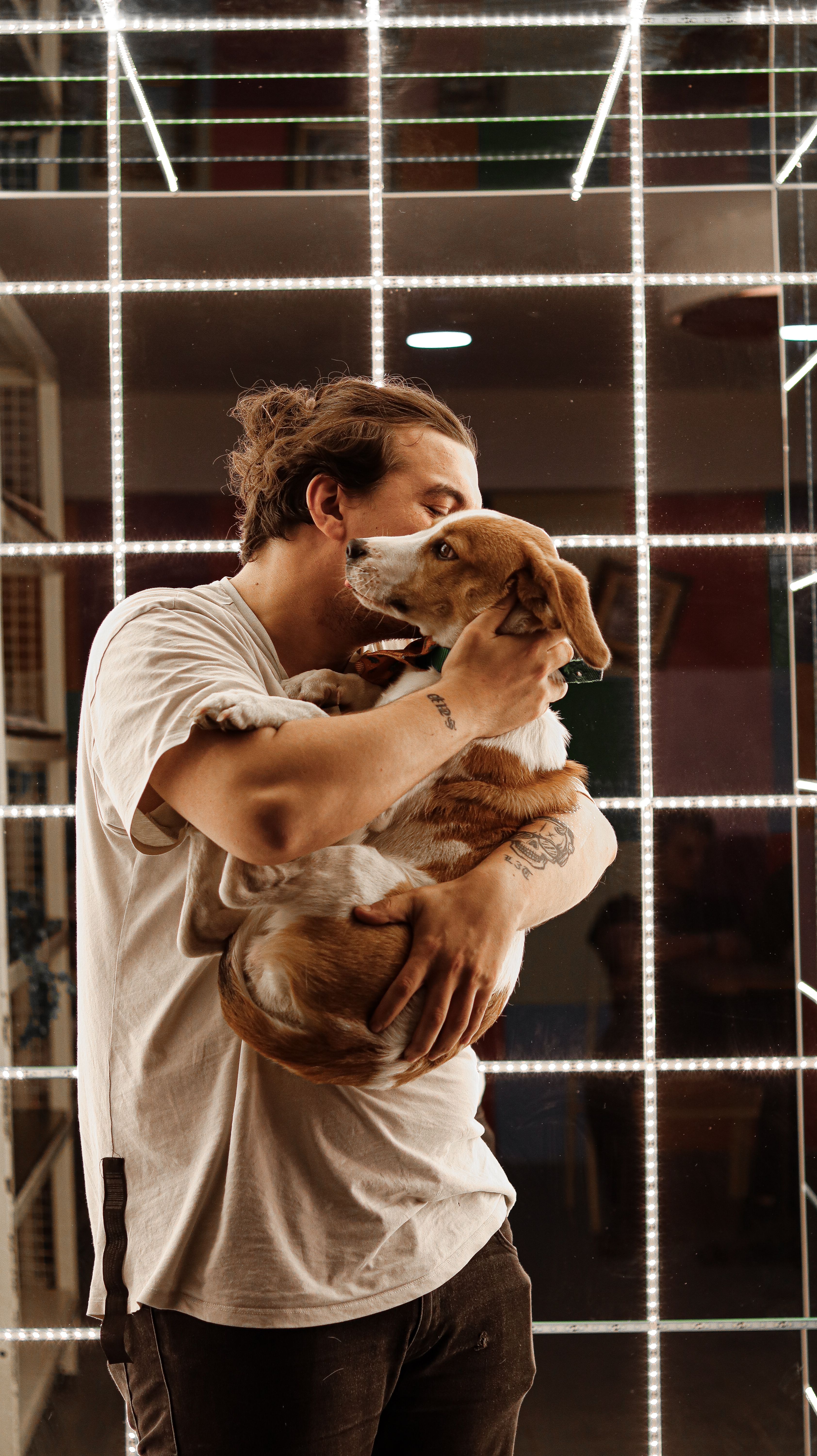 A man warmly embraces his dog in a stylish, well-lit interior setting, creating a heartfelt moment.