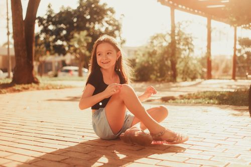 Free A happy girl enjoying a sunny day outdoors on a brick path. Stock Photo