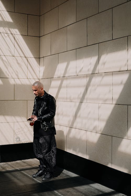 Man in a Black Outfit Standing in front of a Wall 