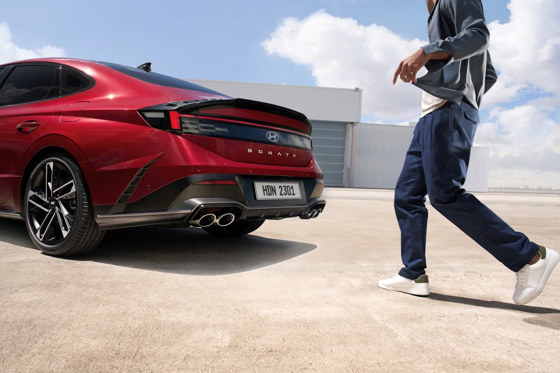 A Man Walking Toward a Red Hyundai Sonata