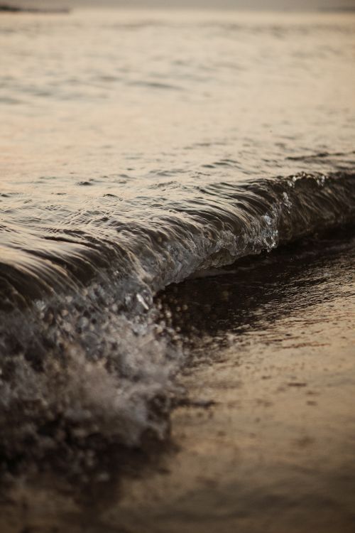 Free A serene close-up of a gentle wave lapping at the shore during sunset in Banda Aceh, Indonesia. Stock Photo