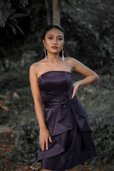 Beautiful Asian woman in a fashionable black dress posing with confidence outdoors.