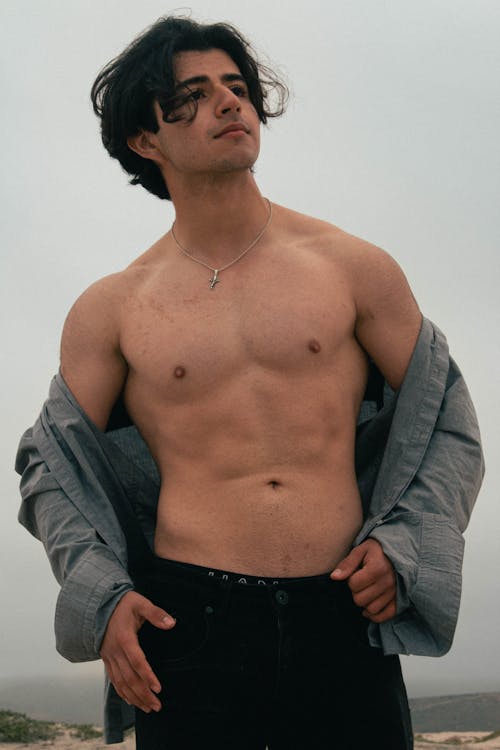 Young Man Posing on the Beach Wearing an Unbuttoned Shirt 