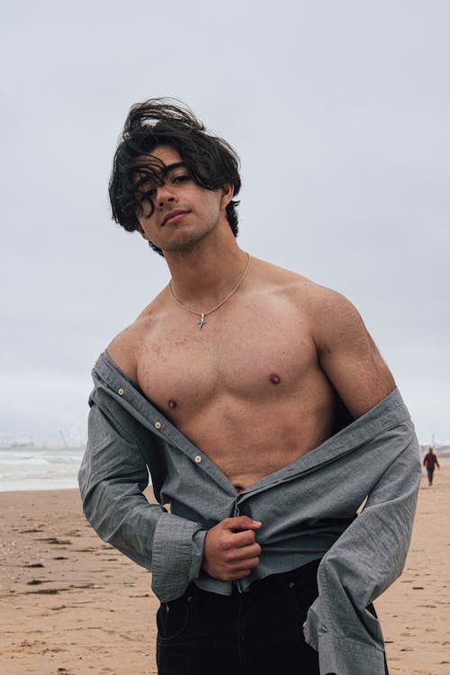 Young Man Posing on the Beach Wearing an Unbuttoned Shirt 