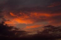 日落景象令人惊叹，充满戏剧性，夜空中红灰相间的云层格外醒目