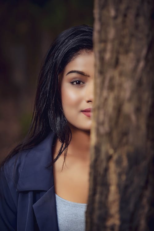 Young Brunette Standing behind the Tree