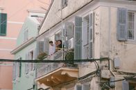 Candid scene of people on a classic Corfu balcony, depicting traditional Greek architecture.