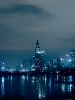 Stunning urban skyline at night with illuminated skyscrapers reflecting on water.