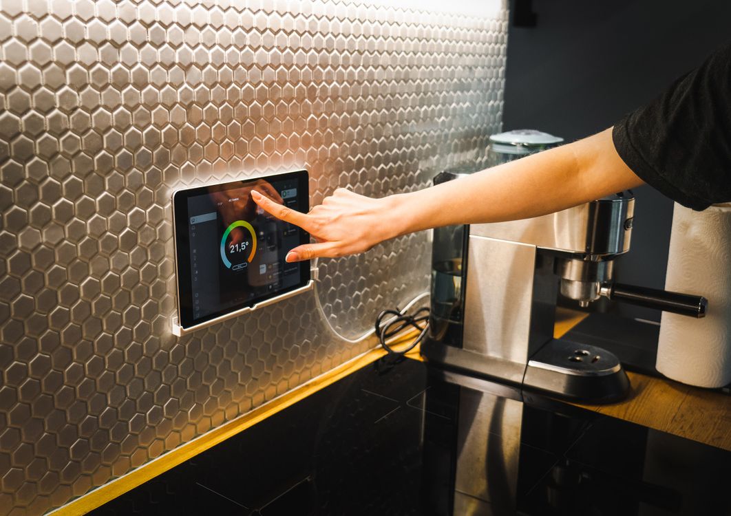 Hand using a tablet to control a smart home system in a kitchen