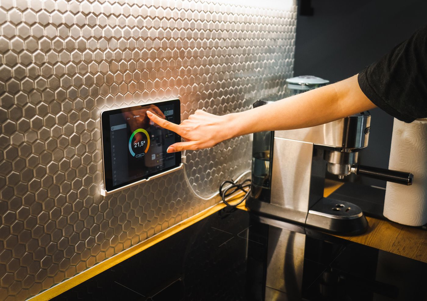 Hand using a wall-mounted control panel in a dark kitchen — photo by Jakub Zerdzicki on Pexels