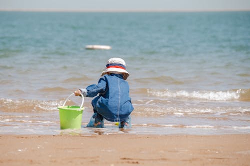 Free A Little Child Playing with the Sand on the Beach  Stock Photo