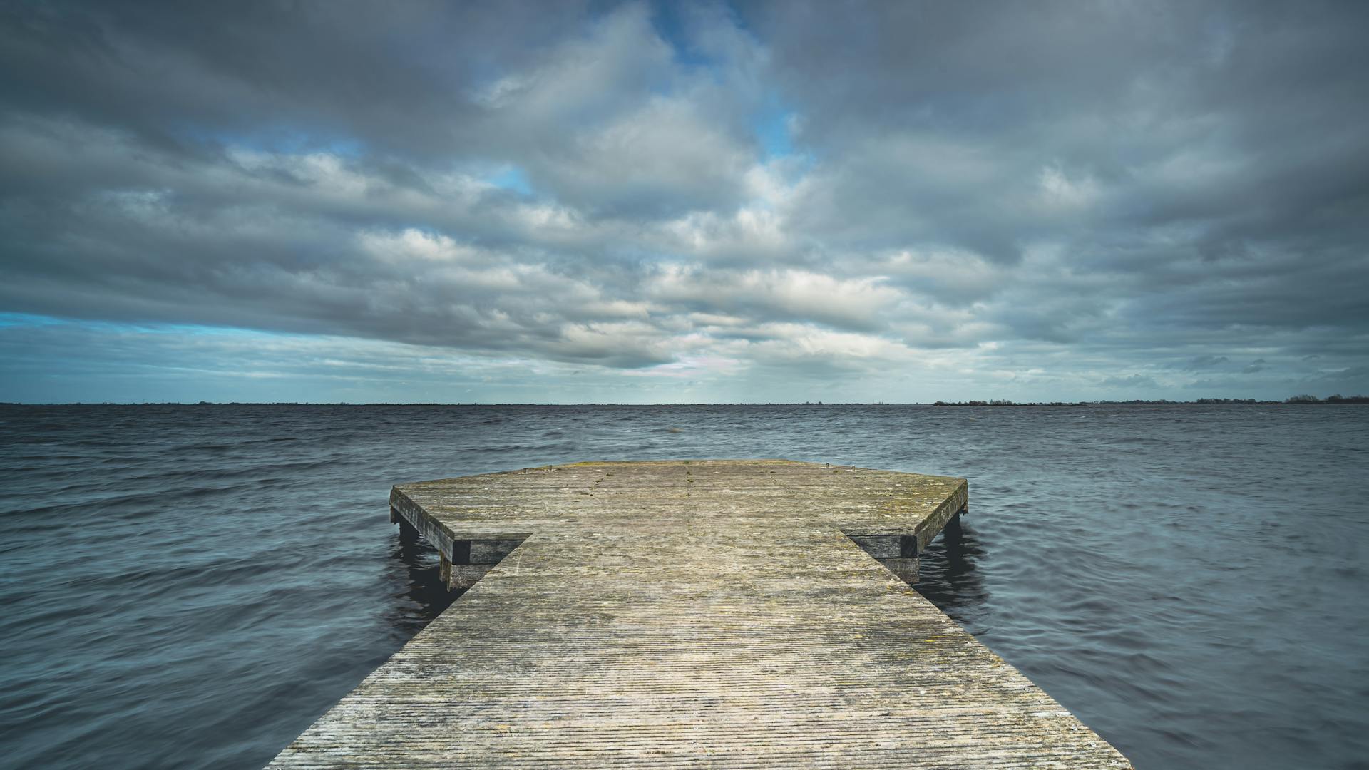 Stormy clouds with dramatic sky above smooth lake made with long exposure photography, Province, Friesland, Holland