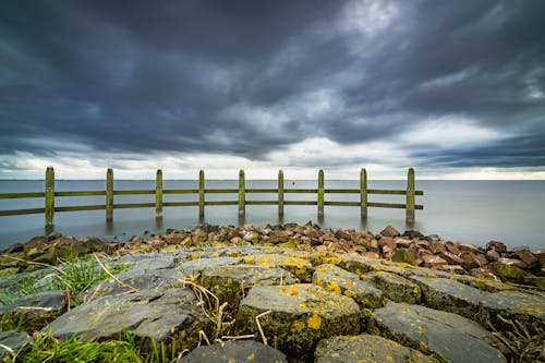 Stormy cloud above pier with wooden breakwater piles