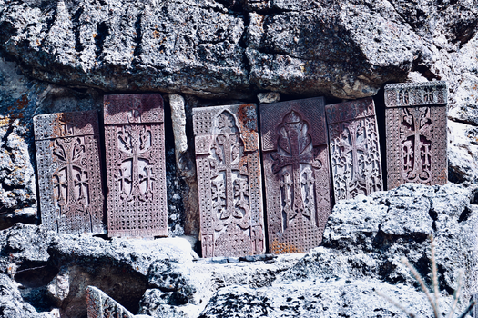 Historic Armenian khachkars carved into eroded rocks, showcasing religious art.