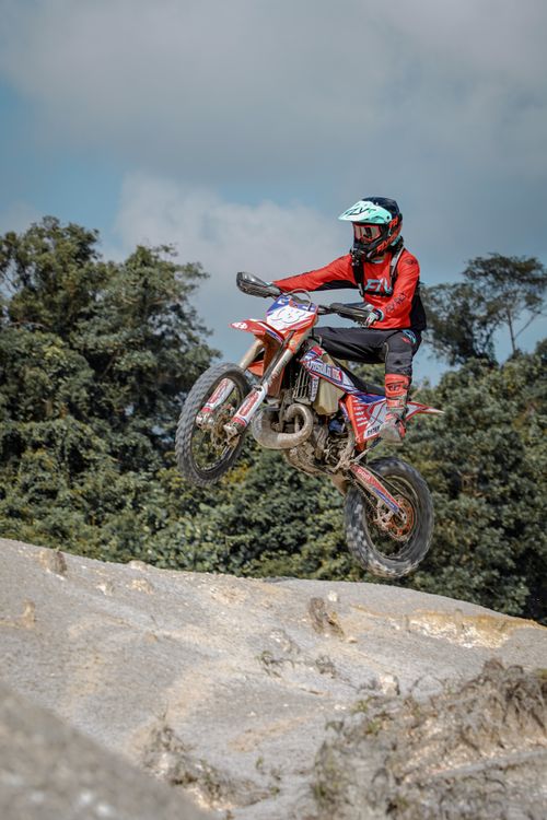 Free Thrilling motocross action with rider soaring over rugged terrain in Manggar, Indonesia. Stock Photo