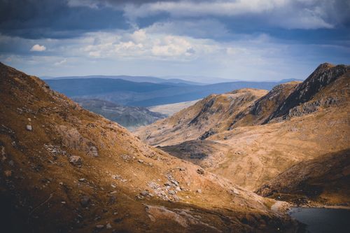 Free Stunning mountain landscape with dramatic clouds casting shadows over rocky terrain. Stock Photo