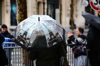 A vibrant Paris street scene featuring an umbrella decorated with Eiffel Tower imagery.