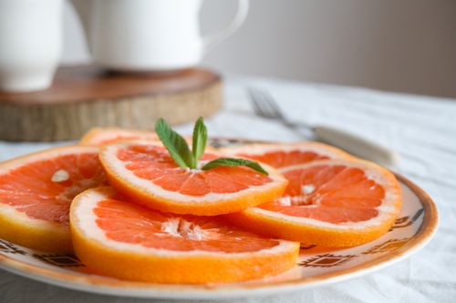 Free Crisp grapefruit slices on a plate with a fresh mint garnish, ready to enjoy. Stock Photo