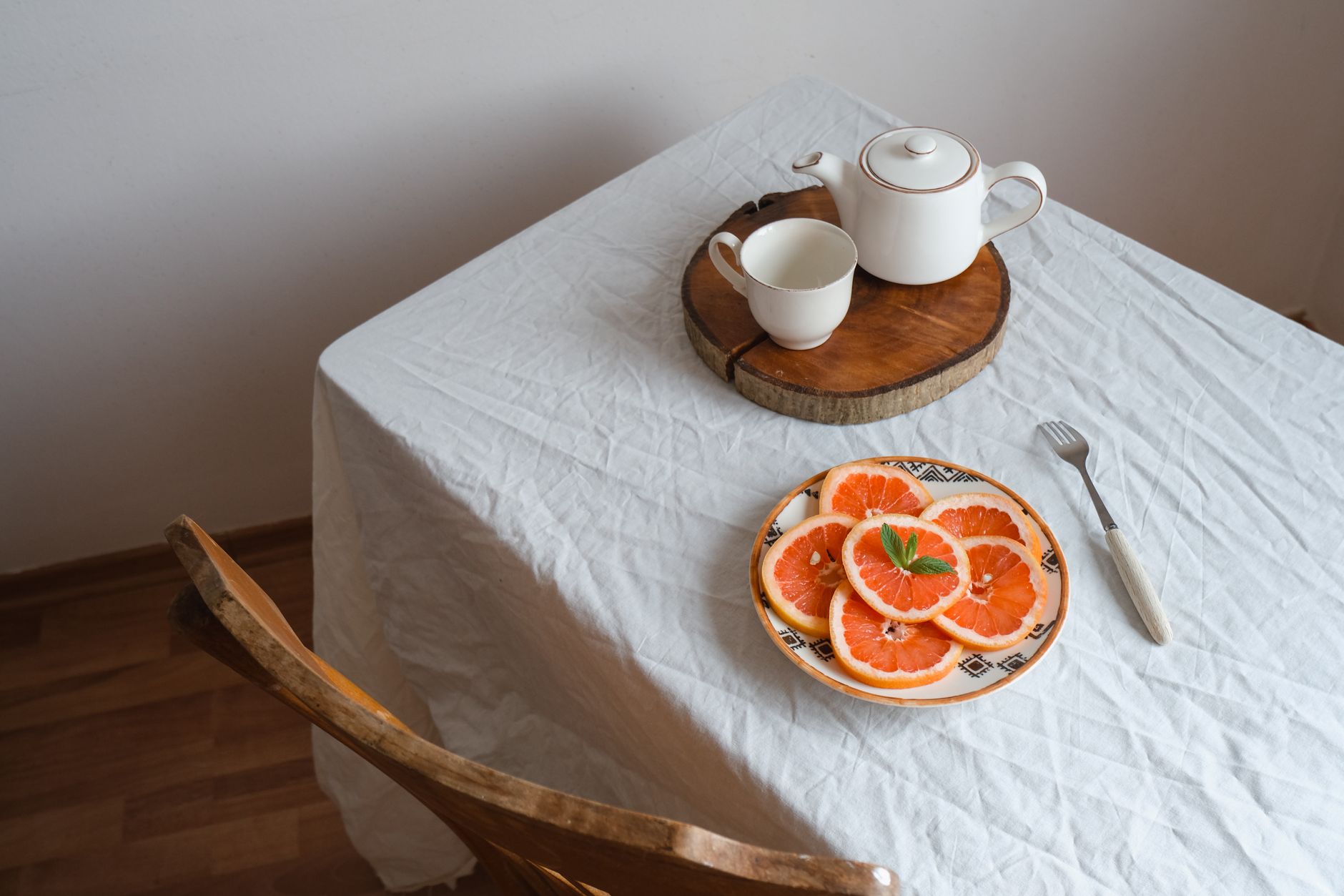 A cozy breakfast setting with sliced grapefruits and a teapot on a wooden tray.