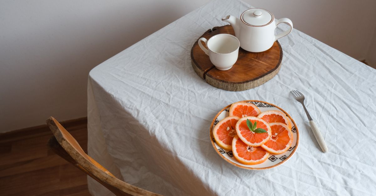 a simple Sunday morning table setting with a Bible, a cup of tea, and fresh fruit