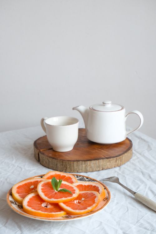 Free A refined table setting featuring a teapot, cup, and fresh orange slices on a white tablecloth. Stock Photo