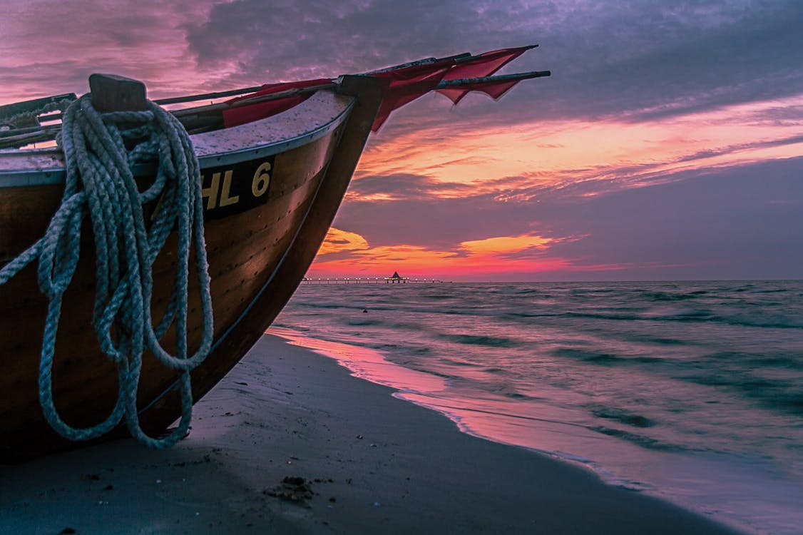Gratis Perahu Kayu Coklat Di Pantai Saat Matahari Terbenam Foto Stok