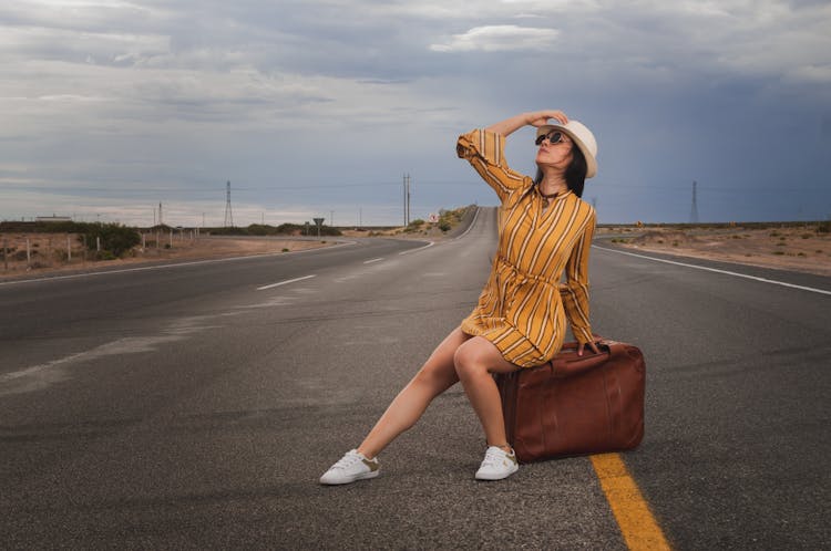 Photo Of Woman Sitting On Luggage Bag