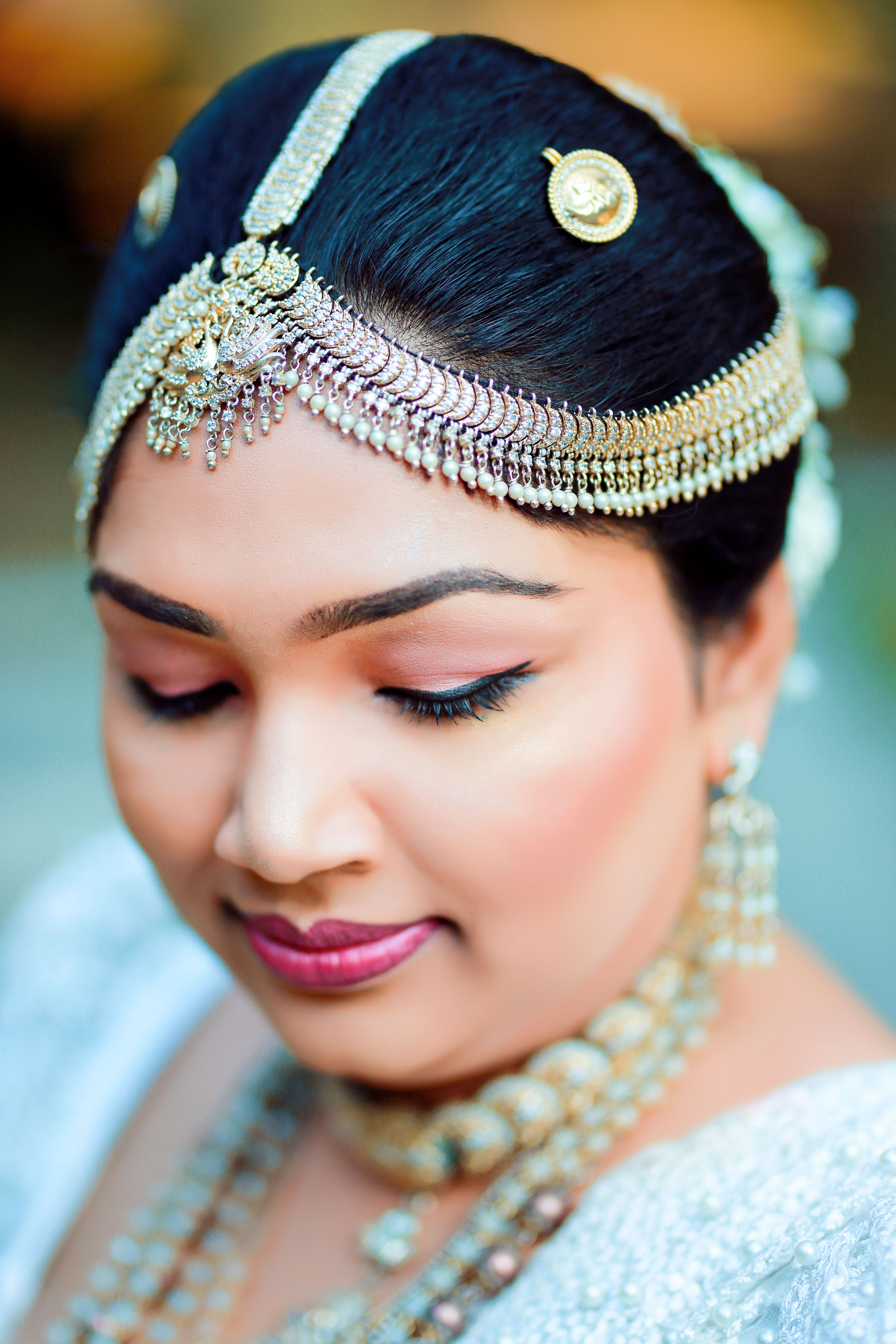 A close-up portrait of a bride wearing traditional Indian jewelry and makeup.