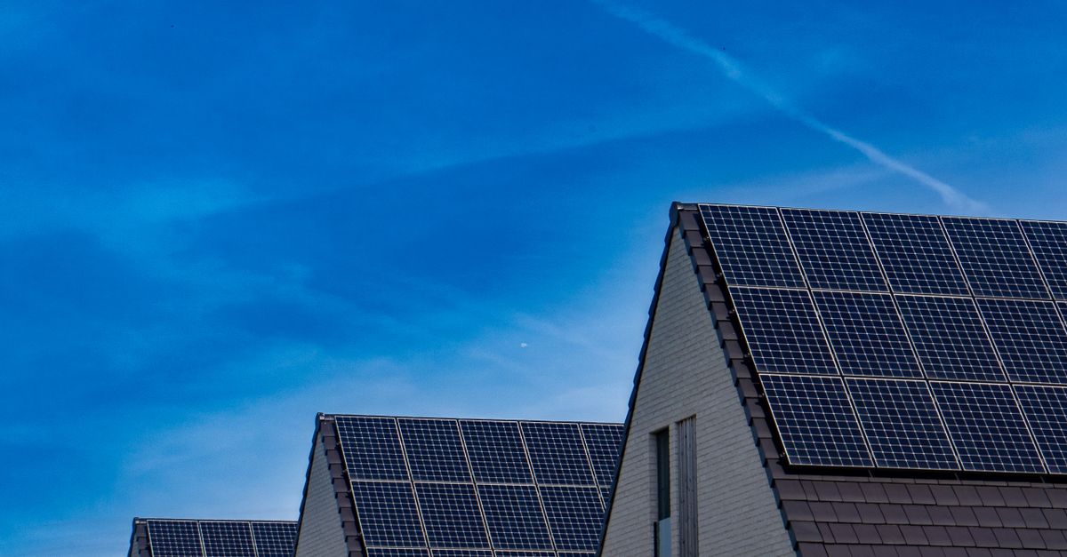 Zwei Einfamilienhäuser mit Solarpanelen auf dem Dach unter blauem Himmel.