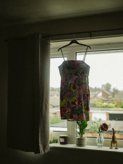 Floral silk mini dress on a hanger by a window — photo by Lisa from Pexels