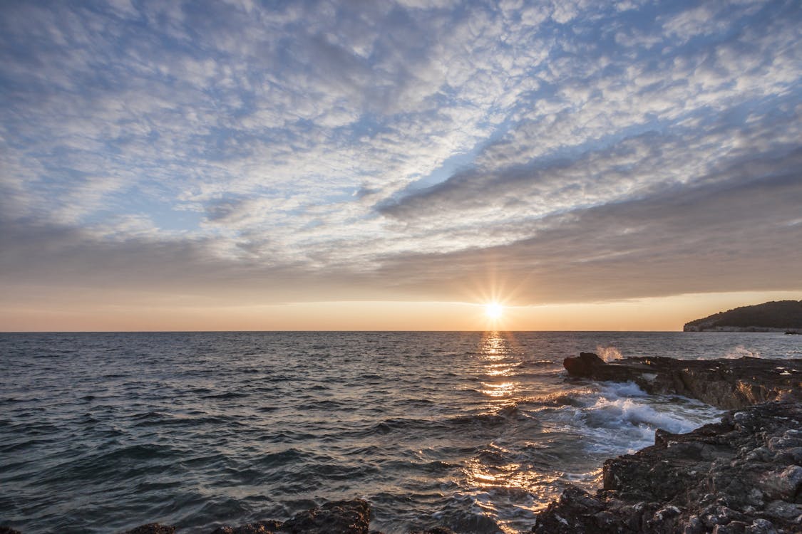 бесплатная Черная скала у моря под закатом Стоковое фото