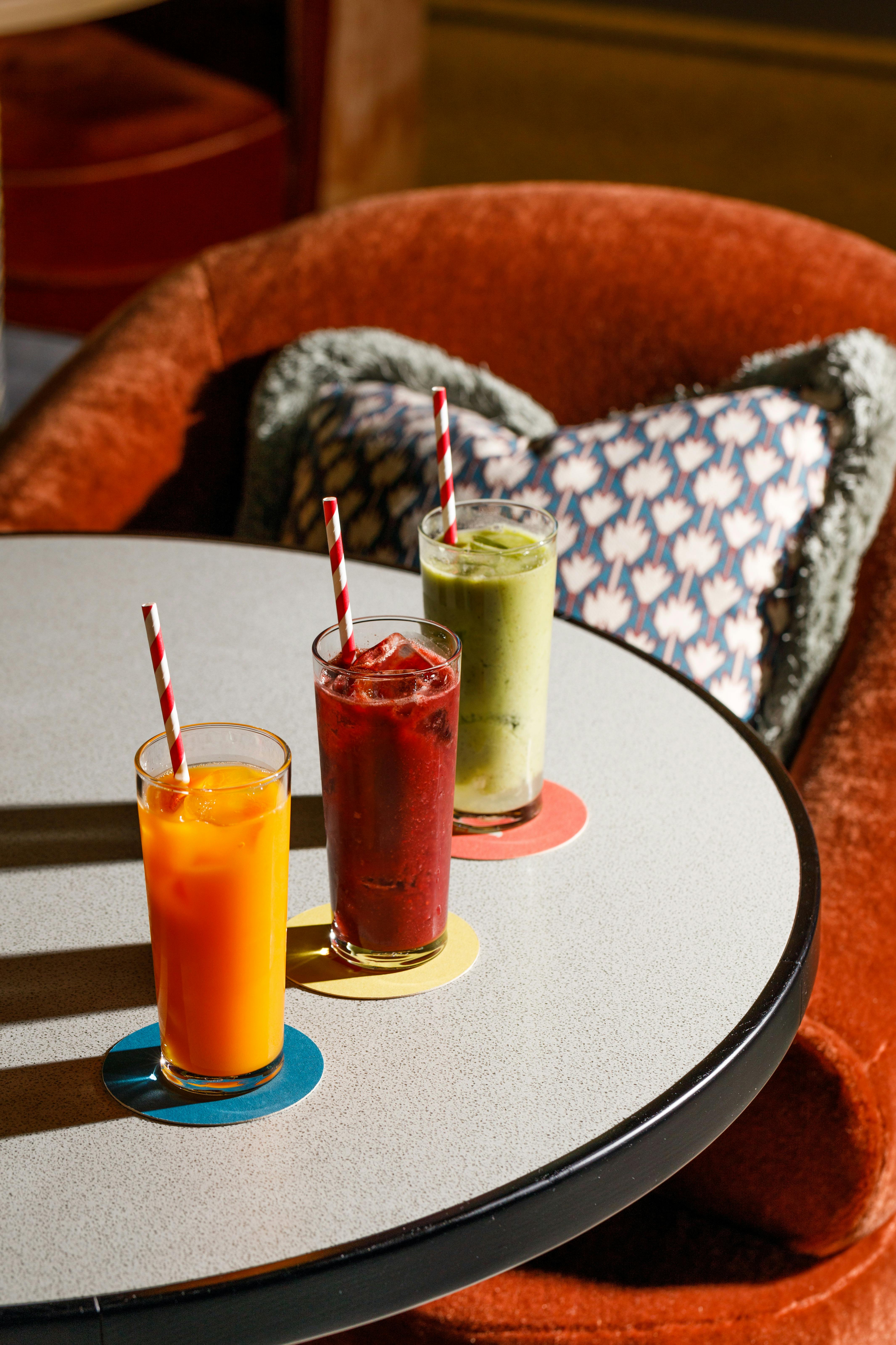 Colorful cocktails with straws on a table in a cozy London lounge.