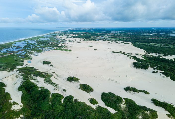 A stunning aerial view of sand dunes and coastline in Fortaleza, Brazil, showcasing desert landscape and ocean view.