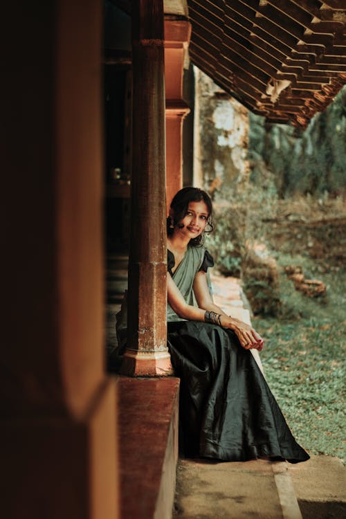 Young Woman in Dark Green Sari Sitting on the Porch