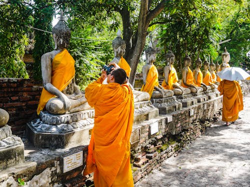 Monk Taking Pictures of Statues of Buddha