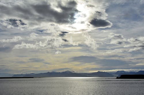 Brown Mountain Beside a Sea Under Grey Cloudy Sky