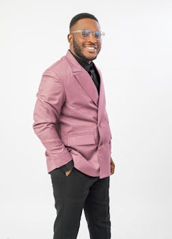 Fashionable man in a pink suit poses confidently on a white background.