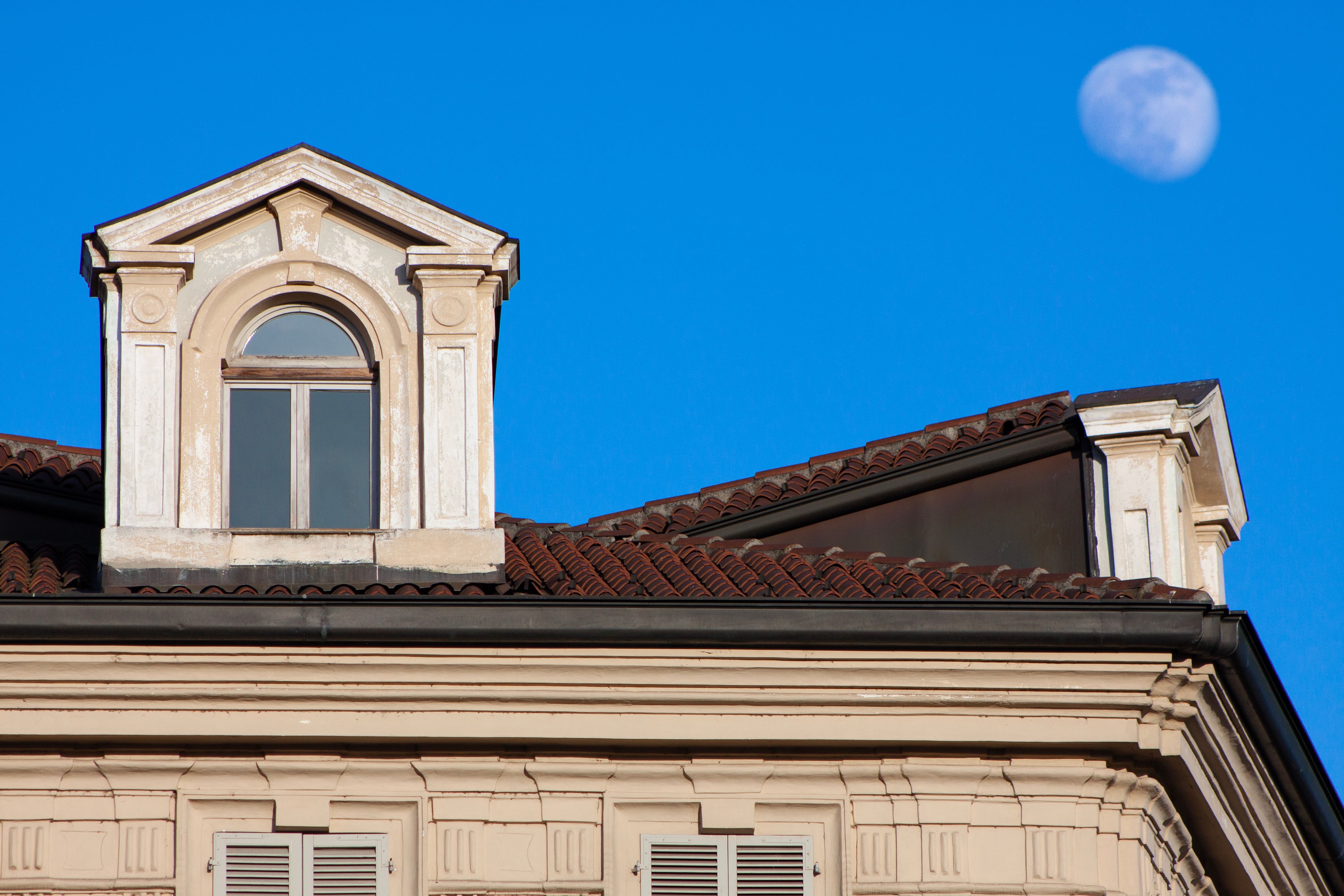 Elegant facade of a historic building in Turin, Italy, with the moon in the background.