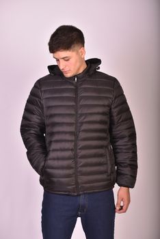Man in a black puffer jacket posing against a neutral background.