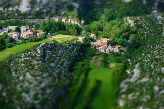 Aerial view of a picturesque rural village nestled between lush green hills and valleys.