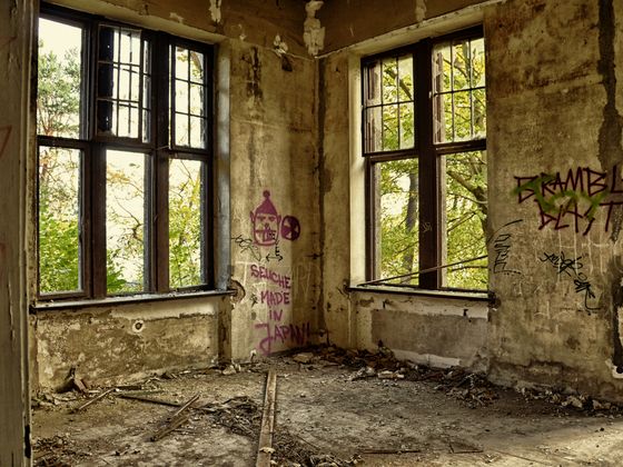 An empty room with graffiti-covered walls and broken windows