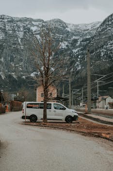 A van parked in a scenic Austrian village with snow-capped mountains.