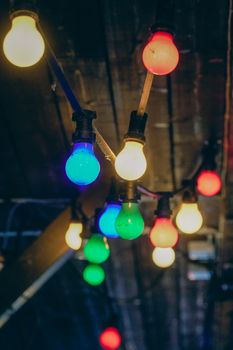 A string of colorful light bulbs hanging from a wooden ceiling creates a festive atmosphere.